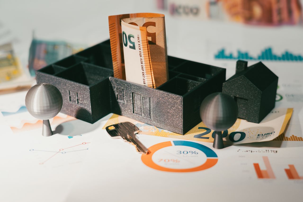 Die wirtschaftliche Rechnung entscheidet: eingesparte Provision gegen erzielbaren Nettoerlös, Zeitaufwand und Risiken. Modellhaus mit Euro-Geldscheinen und Statistik-Diagrammen – wirtschaftliche Abwägung beim Immobilienverkauf ohne Makler